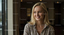 Smiling Blonde Woman in a Plaid Shirt by the Window