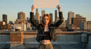 Confident Woman on Rooftop Holding Blank Sign at Sunset