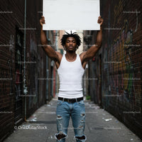 Young Man Holding Blank Sign in Urban Alley