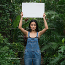 Young Woman Holding a Blank Sign in Lush Tropical Garden