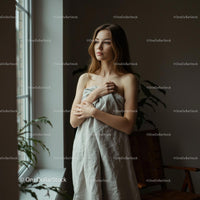 Pensive Woman Wrapped in Linen by Sunny Window