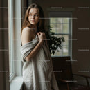 Thoughtful Woman Wrapped in Blanket by Window