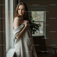 Thoughtful Woman Wrapped in Blanket by Window