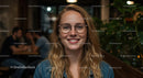 Smiling Young Woman with Glasses in Cozy Café