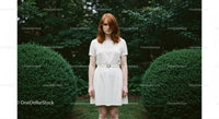 Red-Haired Woman in White Dress Amid Lush Greenery