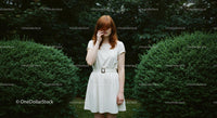 Redhead Girl in White Dress Amid Green Bushes
