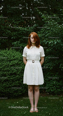 Redhead Woman in White Dress Surrounded by Green Foliage