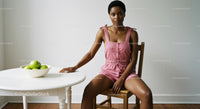 Woman in Pink Jumpsuit Sitting by White Table with Apples