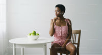 Thoughtful Woman in Pink Dress with Green Apples