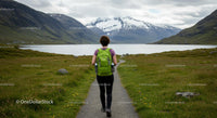 Woman Hiking with Green Backpack in Scenic Mountain Landscape
