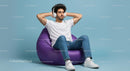 Young Man Relaxing on Purple Bean Bag in Headphones