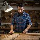 Carpenter Measuring Wood in Workshop