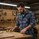 Focused Carpenter Measuring Wood in a Workshop