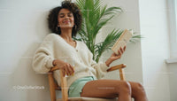 Relaxed Woman Reading by Indoor Palm in Cozy Home Setting