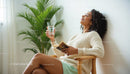 Woman Relaxing with Book and Glass of Water by Palm Plant