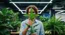 Man Playfully Hiding Behind Lush Green Plant in Office