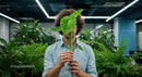 Person Holding Monstera Leaf in Modern Office