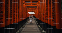Man Walking Through Vibrant Orange Torii Gates in Kyoto