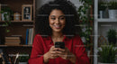 Woman with Curly Hair Smiling While Holding Smartphone