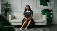 Smiling Woman in Polka Dot Dress on a White Sofa in Modern Living Room