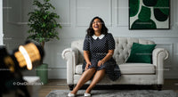 Smiling Woman in Polka Dot Dress Sitting on a Cozy Sofa