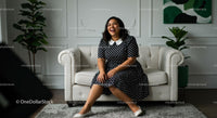 Smiling Woman in Polka Dot Dress on White Sofa