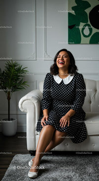 Smiling Woman Relaxing on a Sofa in Polka Dot Dress