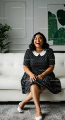 Smiling Woman in Polka Dot Dress Sitting on White Sofa