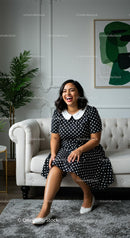 Cheerful Woman in Polka Dot Dress on Stylish Sofa