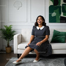 Smiling Woman in Polka Dot Dress on Modern Sofa