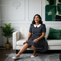 Smiling Woman in Polka Dot Dress on Modern Sofa