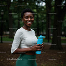 Smiling Woman with Water Bottle in Lush Green Park