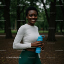 Smiling Woman with Water Bottle in Lush Green Park