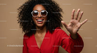 Smiling Woman with Curly Hair and Sunglasses Waving