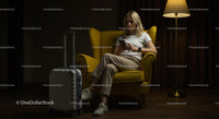 Woman Relaxing in Yellow Armchair with Suitcase and Smartphone