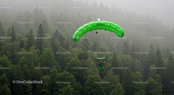Parachutist Soaring Over Misty Green Forest Landscape