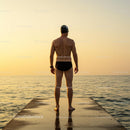 Swimmer Standing on Pier at Sunset Over Calm Ocean