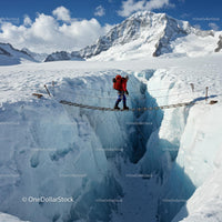 Mountaineer Crossing Ice Bridge Over Deep Glacier Crevasse