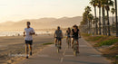 People Cycling and Jogging Along a Scenic Beach Path at Sunset