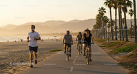 People Cycling and Jogging Along a Scenic Beach Path at Sunset