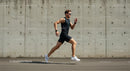 Athletic Man Running Against a Concrete Wall in Urban Setting