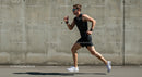 Male Athlete Running Against Concrete Wall on Sunny Day