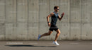 Male Athlete Running Against Concrete Wall on Sunny Day