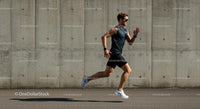 Male Athlete Running Against Concrete Wall on Sunny Day