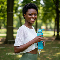 Smiling Woman Outdoors with Water Bottle in a Lush Park