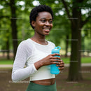 Smiling Woman with Water Bottle in Lush Green Park