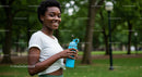 Smiling Woman Holding Water Bottle in a Summer Park