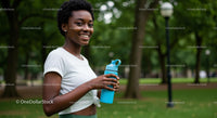 Smiling Woman Holding Water Bottle in a Summer Park