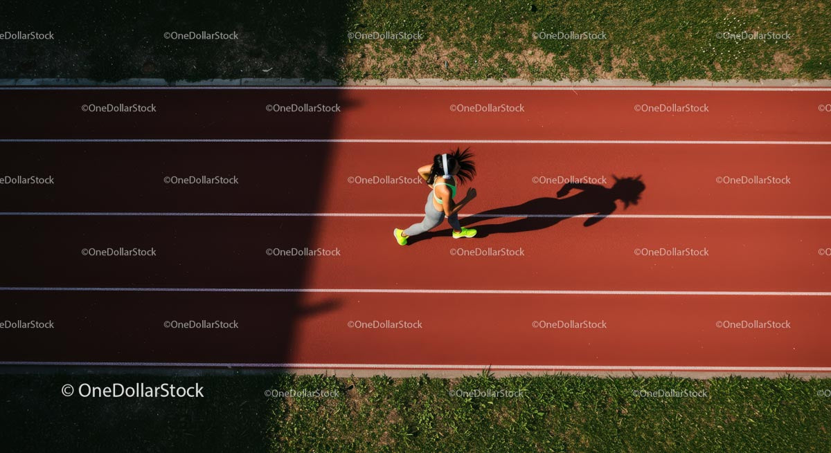 Widok z lotu ptaka na kobietę biegnącą po czerwonej bieżni sportowej