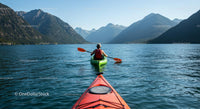 Kayaker Exploring Tranquil Mountain Lake Amidst Majestic Peaks